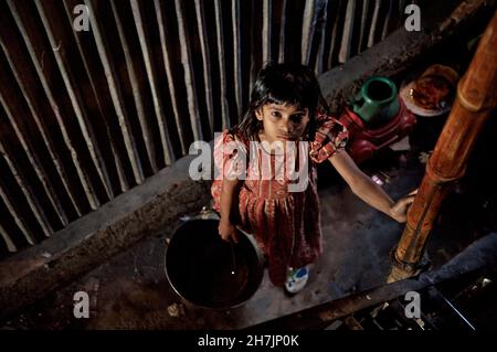 Un enfant tient un seau rempli d'eau, recueilli à la pompe à main commune, dans un bidonville, près du fleuve Buriganga, dans le Vieux Dhaka, au Bangladesh.Février 2 Banque D'Images