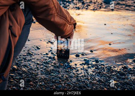 Un homme prend des photos d'un beau coucher de soleil sur la mer Banque D'Images