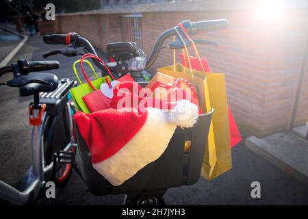 Shopping de Noël.Panier à vélo plein de cadeaux de Noël et de sacs cabas colorés.Chapeau du Père Noël reposant sur les cadeaux. Banque D'Images