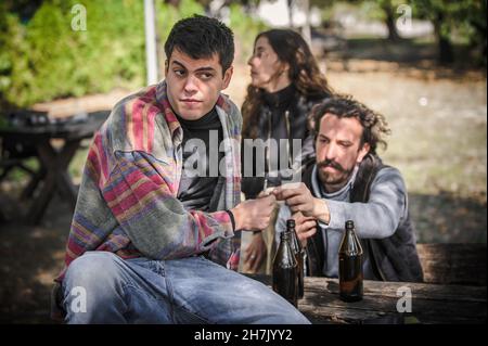 Les jeunes amis gardent la montre, regardent autour et essayent de cacher pendant que donne de la main à la main les uns les autres joint ganja dans le parc public en plein air.Fumer du cannabis ma Banque D'Images