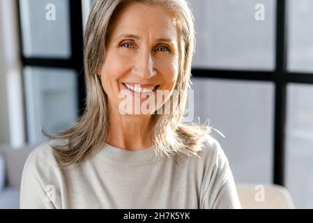 Portrait en gros plan d'une femme d'affaires très gaie dans un bureau moderne et lumineux, d'une femme d'affaires souriante et mûre, qui regarde l'appareil photo avec un sourire éclatant Banque D'Images