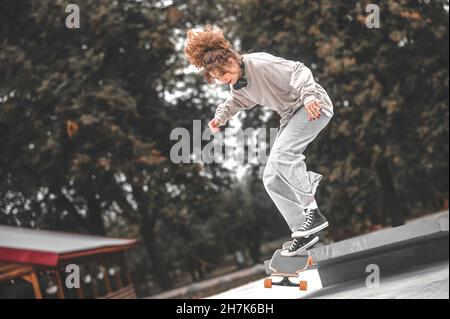 Une fille sur un skateboard au moment de sauter du tremplin Banque D'Images