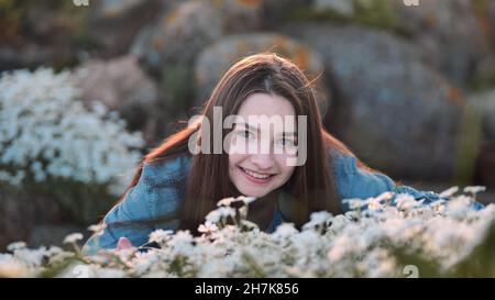 Une fille à poil long se hante de fleurs blanches et de sourires. Banque D'Images