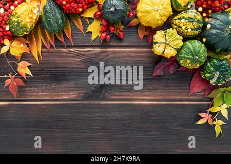 Arrière-plan d'automne avec citrouilles décoratives et feuilles colorées sur fond de bois sombre.Joyeux Thanksgiving concept.Plan à plat, espace de copie pour le texte Banque D'Images