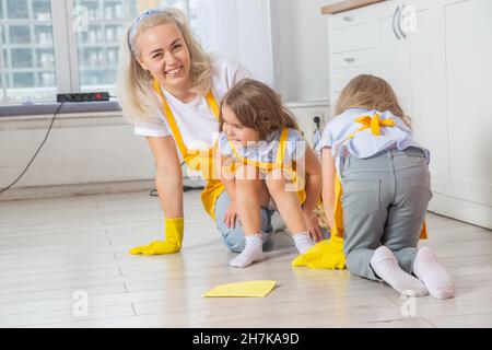 Souriant maman caucasienne enseignant filles humide de nettoyage de la cuisine.Deux générations de femmes ensemble dans la cuisine. Banque D'Images