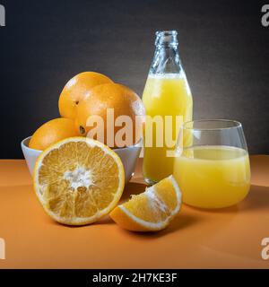 Helsinki / Finlande - gros plan des oranges humides et bouteille de jus d'orange en verre sur la table. Banque D'Images