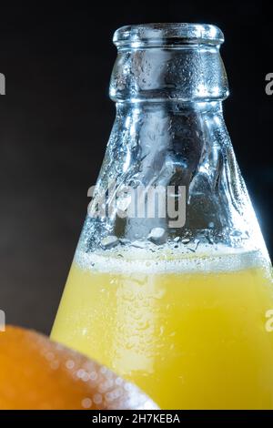 Helsinki / Finlande - gros plan des oranges humides et bouteille de jus d'orange en verre sur la table. Banque D'Images
