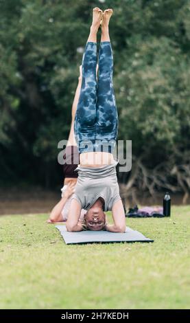 Personnes pratiquant le yoga en position inverse dans un parc Banque D'Images