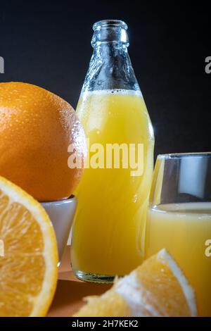 Helsinki / Finlande - gros plan des oranges humides et bouteille de jus d'orange en verre sur la table. Banque D'Images