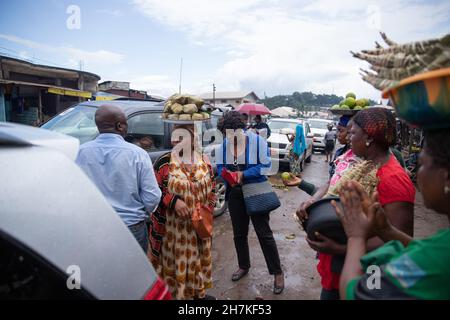 Une femme africaine avec des paniers de nourriture sur leur tête vend leurs produits dans la rue, la vie traditionnelle au Cameroun Banque D'Images