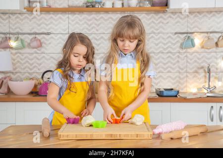 Une maman caucasienne souriante enseignant aux filles de cuisiner ensemble dans la cuisine.Concept de cuisine maison Banque D'Images