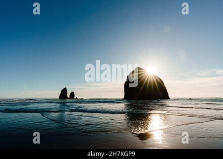 Le soleil se couche derrière le rocher de haystack sur Cannon Beach dans l'Oregon Banque D'Images