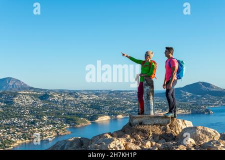 Deux randonneurs se tiennent au sommet au-dessus de la mer méditerranée et des collines et regardent, Calpe, province d'Alicante, Espagne Banque D'Images