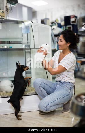 femme avec lapins et petit chien dans la boutique d'animaux Banque D'Images