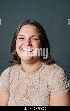 Jeune femme riant sur fond gris Banque D'Images