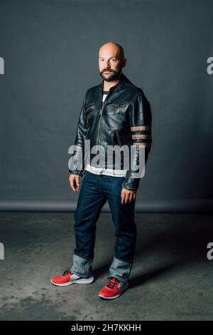 Homme chauve plein d'assurance debout devant un fond gris Banque D'Images