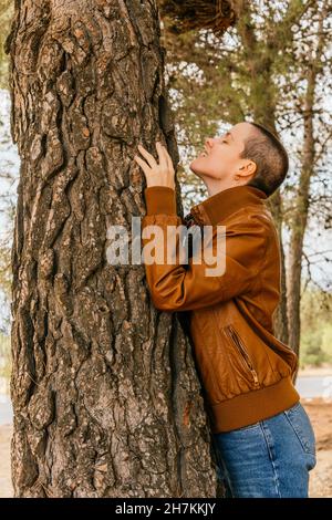 Femme souriante portant une veste qui épouse l'arbre Banque D'Images