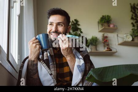 Homme souriant et beau avec châle embrassant le chien Akita dans le salon Banque D'Images