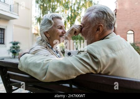 Femme âgée assise sur le banc tirant sur le nez de l'homme Banque D'Images