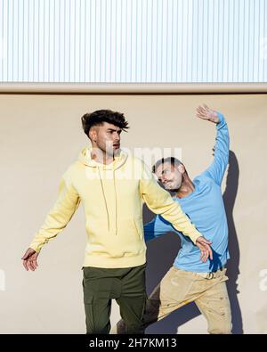 Des amis masculins confiants dansent ensemble devant la toile de fond par beau temps Banque D'Images