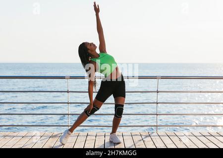 Jeune sportswoman avec la main levée exercice par la main pendant la journée ensoleillée Banque D'Images