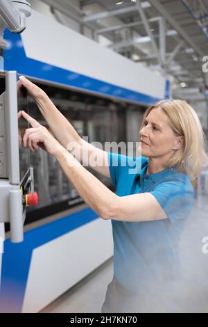 Souriante femme professionnelle avec des machines d'exploitation de tablette numérique en usine Banque D'Images