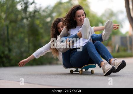 Amis féminins assis sur le mur de soutènement Banque D'Images