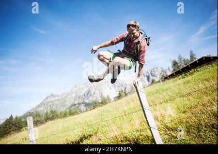 Des parents heureux tenant les mains de leur fils tout en randonnée sur la prairie alpine pendant les vacances Banque D'Images