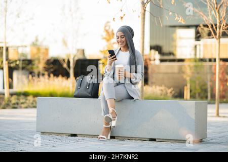 Une jeune femme d'affaires confiante portant le hijab debout avec les bras croisés devant le mur Banque D'Images