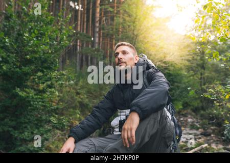 Mâle touriste regardant à travers des jumelles dans la forêt Banque D'Images