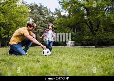 Famille jouant avec le ballon de football sur l'herbe Banque D'Images