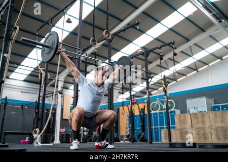 Athlète masculin faisant des squats dans la salle de gym Banque D'Images