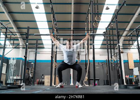 Athlète masculin ciblé tenant la barbell tout en faisant de l'exercice dans la salle de gym Banque D'Images