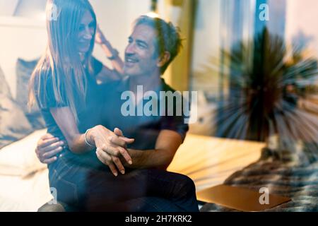 Femme mûre assise sur les genoux de l'homme dans la chambre Banque D'Images