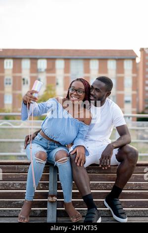 Un jeune couple souriant prend le selfie sur le banc Banque D'Images