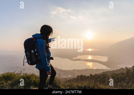 Randonneur pointant vers le coucher du soleil pendant la randonnée en montagne Banque D'Images