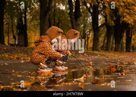 Des jumeaux se croquant à la flaque dans le parc d'automne