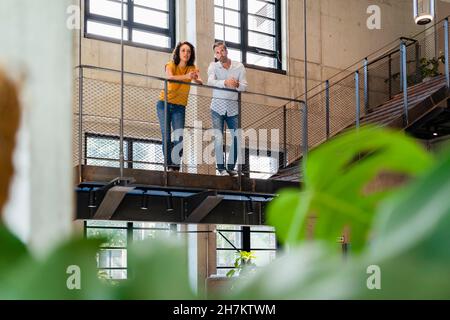 Des collègues réfléchis penchent sur des rampes d'escalier Banque D'Images