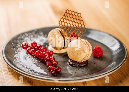 Photo studio d'une assiette de biscuits macarons gastronomiques aux baies de cassis Banque D'Images