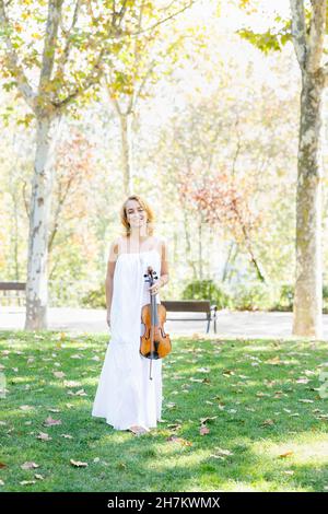 Jeune violoniste tenant du violon sur l'herbe Banque D'Images