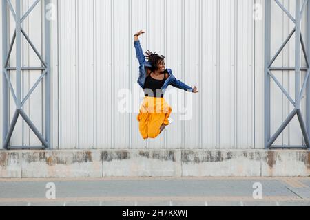 Femme insouciante sautant devant le mur Banque D'Images