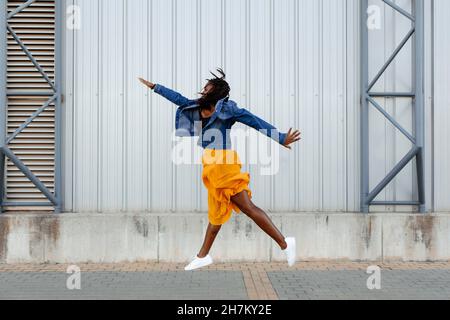 Une femme joyeuse sautant devant le mur Banque D'Images