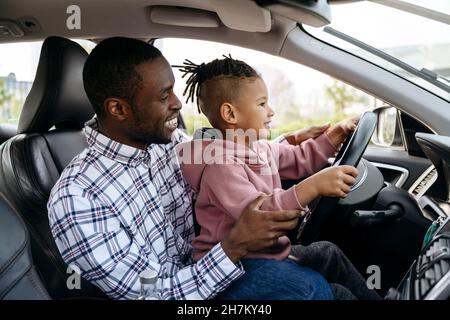 Père et fils souriants jouant avec le volant dans la voiture Banque D'Images