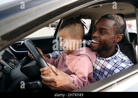 Père et fils heureux jouant avec le volant dans la voiture Banque D'Images