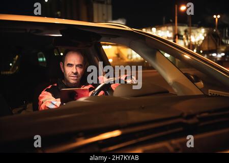 Ingénieur utilisant une tablette PC en voiture la nuit Banque D'Images