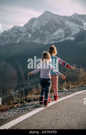 Filles espiègle avec les bras débordés marche sur le marquage de la route Banque D'Images