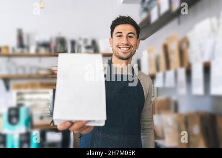 Un garçon verse du lait dans une tasse de café au café Banque D'Images