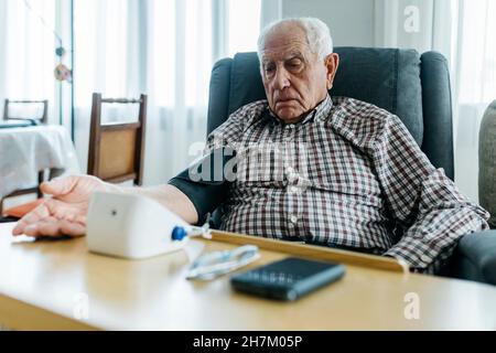 Homme vérifiant la pression artérielle sur la table à la maison Banque D'Images