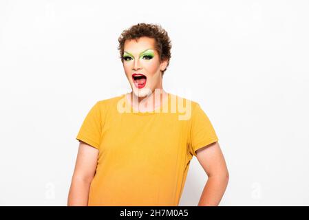 Un homme surpris avec le maquillage de Drag Queen sur le visage devant un fond blanc Banque D'Images