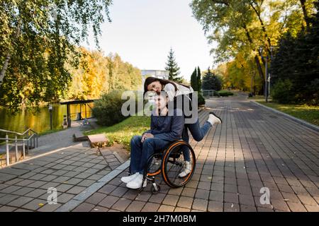 Femme embrassant un homme handicapé en fauteuil roulant de derrière Banque D'Images